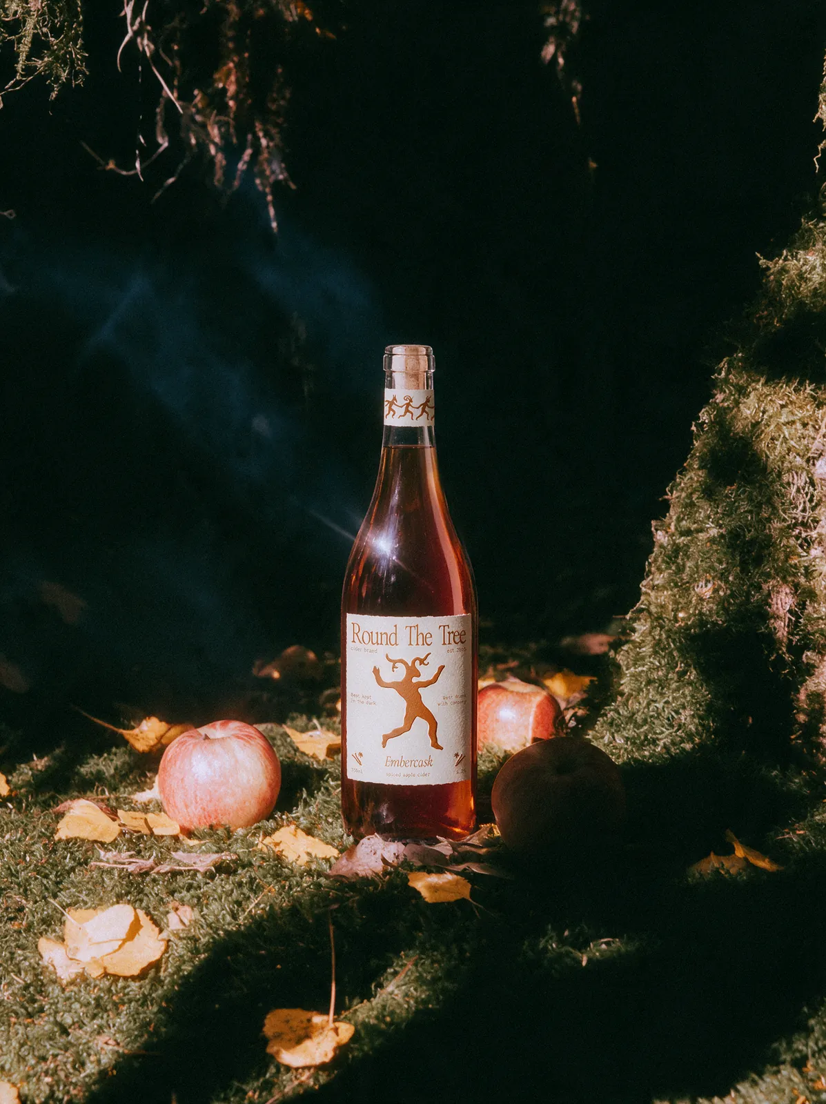Round The Tree cider bottle in a moss-covered orchard at night