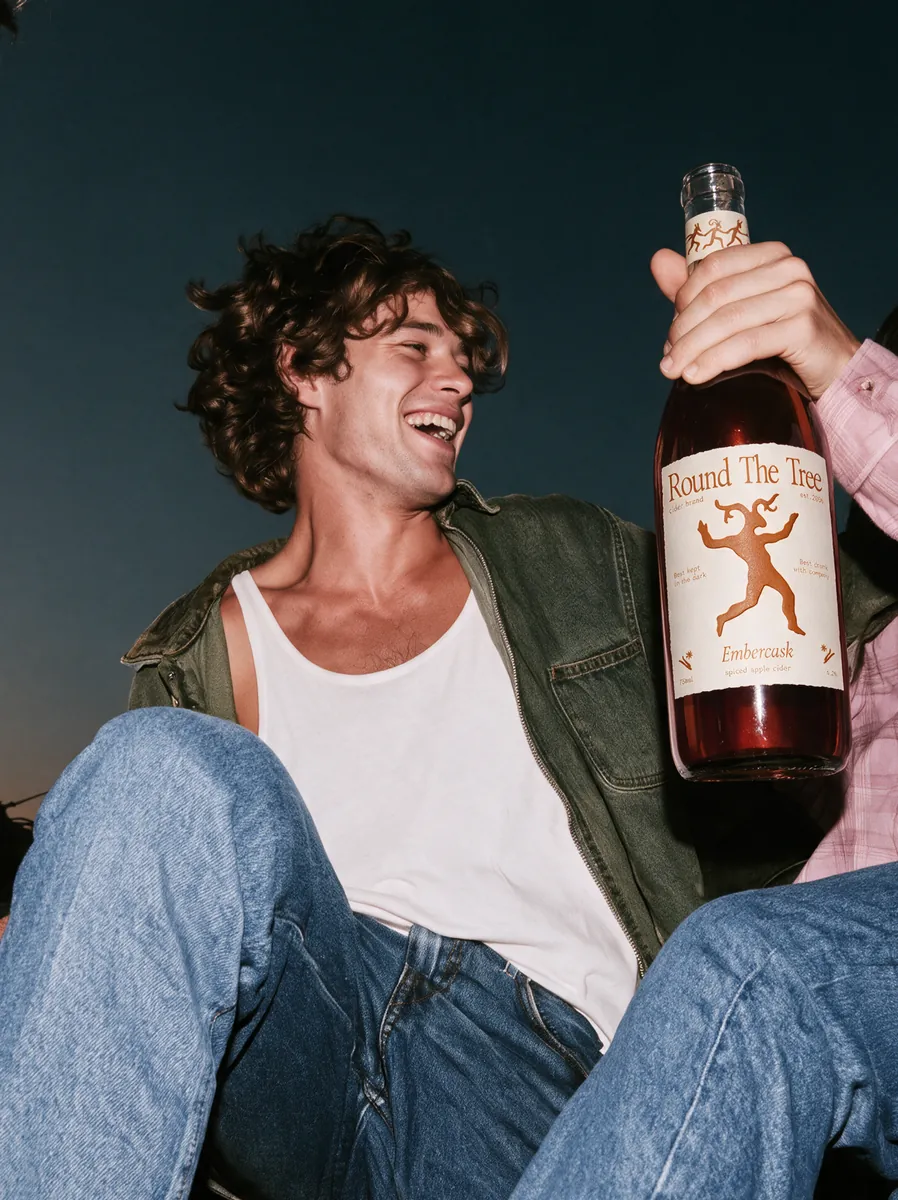 Man laughing with a bottle of Round The Tree cider