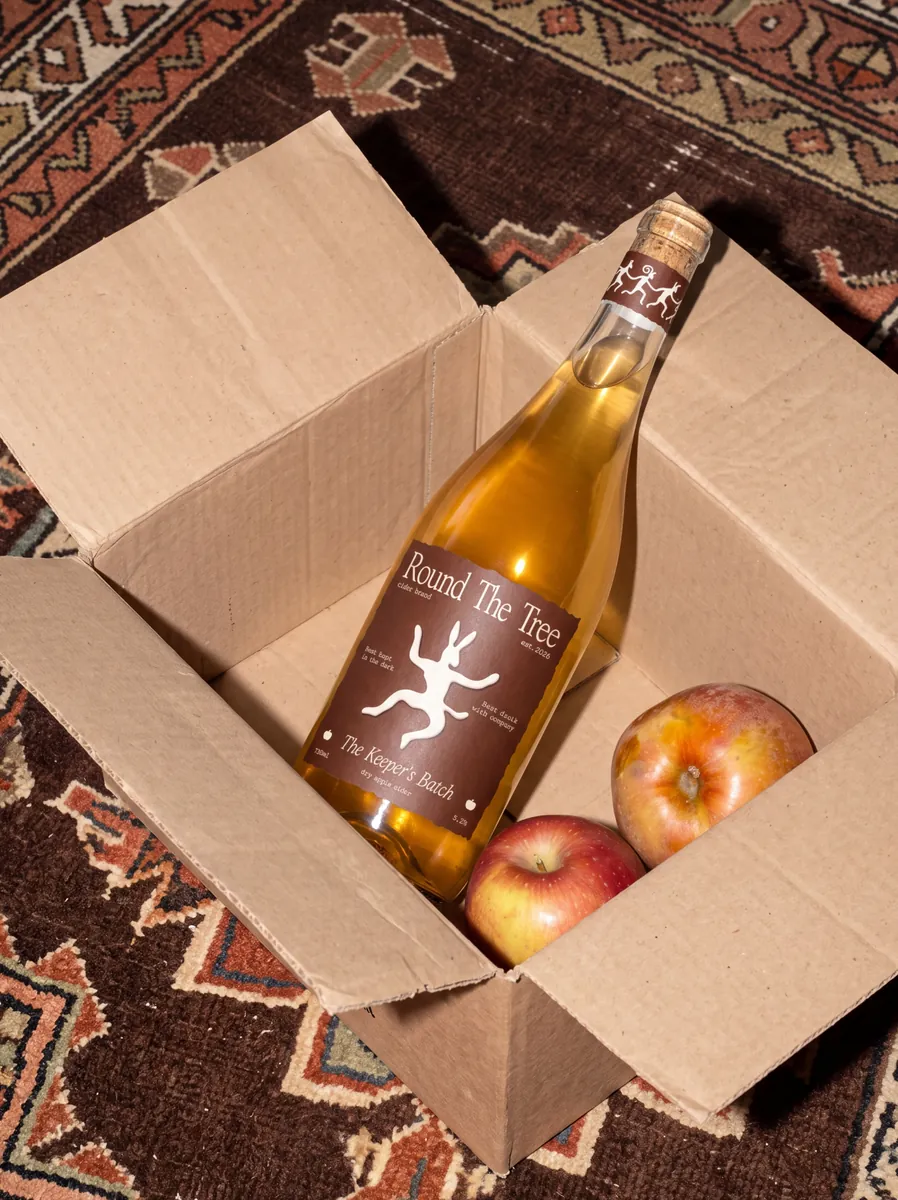 Cider bottle in a cardboard box with apples